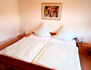 a bed with white sheets and a picture on the wall at Ferienwohnung Am Saarbogen 