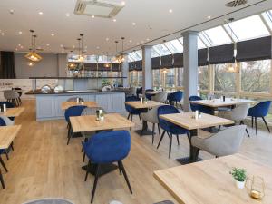 un restaurante con mesas de madera y sillas azules en DORMERO Hotel Meerbusch, en Meerbusch