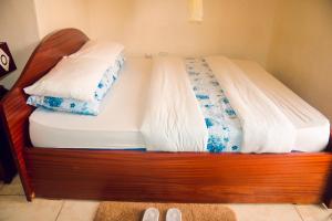 a wooden bed with two pillows on top of it at Light House Hotel in Huye
