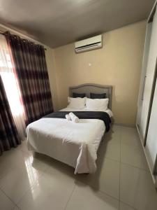 - une chambre avec un lit doté de draps et d'oreillers blancs dans l'établissement Ivwananji I - Kat-Onga Apartments, à Lusaka