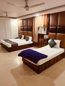 a bedroom with two beds and a tv on the wall at Hotel Cozy Cave Delhi Aiport in New Delhi