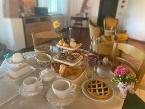 una mesa con pastas, tazas y platos de comida en Il Casale delle Rose, en Paganico