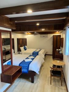 a bedroom with two beds and a table and a mirror at NamKhan Riverside in Luang Prabang