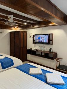 a bedroom with two beds and a flat screen tv at NamKhan Riverside in Luang Prabang
