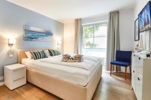 una camera con un grande letto e una sedia blu di Strandallee 200 - App. 309 a Timmendorfer Strand