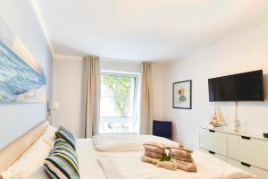 um quarto branco com uma cama e uma televisão em Strandallee 200 - App. 309 em Timmendorfer Strand