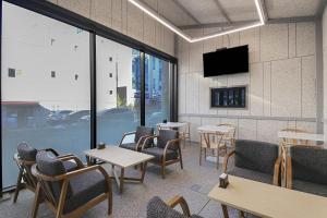 a restaurant with tables and chairs and a tv on the wall at GwangJu Gwangsangu Hanam HoundHotel in Gwangju