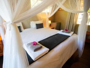 a bedroom with a white bed with towels on it at Kum Kula Lodge in Hoedspruit