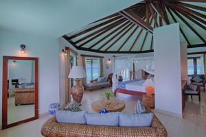 uma sala de estar com uma cama e um sofá num quarto em Kihaa Maldives em Baa Atoll