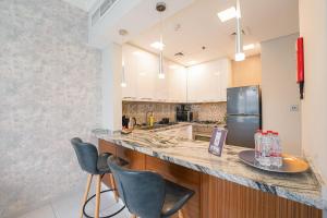 a kitchen with a counter with chairs and a refrigerator at KeyHost - Regent Court JVC - K420 in Dubai