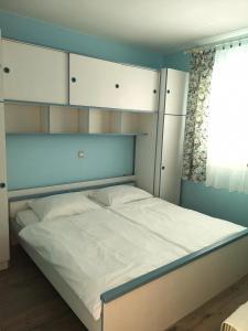a bed in a room with white cabinets and a window at Apartment in Lopar with sea view, terrace, washing machine, dishwasher 593-1 in Lopar