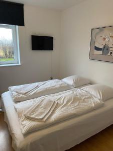 a bed with white sheets and a television on a wall at OnlySleep Femern in Holeby