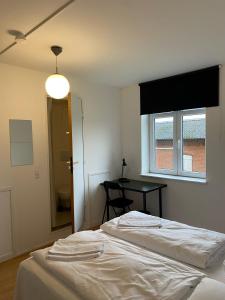 a bedroom with two beds and a window and a table at OnlySleep Femern in Holeby