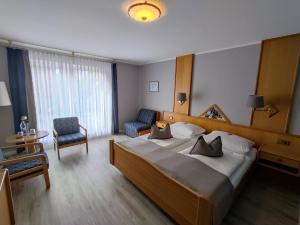 a hotel room with a large bed and a chair at Hotel Zum Märchenwald in Lingen