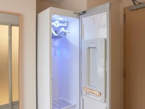 a white refrigerator in a room next to a mirror at Henn na Hotel Kagoshima Tenmonkan in Kagoshima