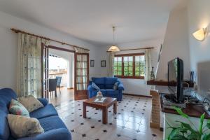 a living room with blue couches and a tv at VILLA MARIA vistas al mar y piscina privada in Son Bou