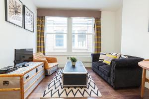 a living room with a couch and a table at Clockwork London Flats in London