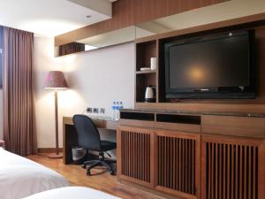Habitación de hotel con TV y escritorio con silla. en Guide Hotel Taipei Bade, en Taipéi