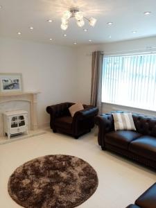 a living room with two leather couches and a fireplace at Anglesey home by the sea in Amlwch