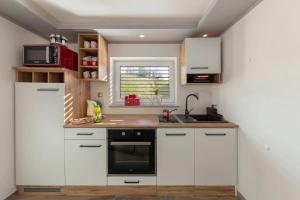 Una cocina con gabinetes blancos y un fregadero. en Holiday House Vikend, en Polzela