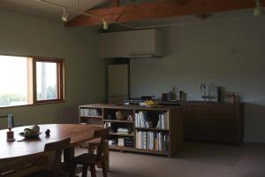 een keuken met een tafel en een boekenplank bij WORM in Awaji