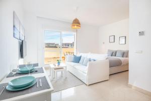 a white living room with a couch and a table at Renthas Añoreta Golf Beach in Torre de Benagalbón