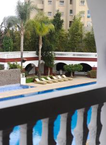 eine Brücke über einen Pool mit Palmen und ein Gebäude in der Unterkunft Targafit Hotel & Hammam in Marrakesch