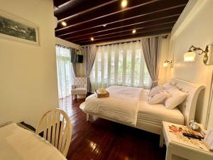 a bedroom with a bed and a table and a chair at Zane Balcony House Ranong Hotel เซน บัลโคนี่ เฮ้าส์ ระนอง in Ban Lum Than