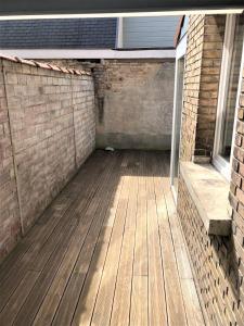 an outdoor patio with a wooden floor and a brick wall at Maison de ville avec cour Place Luton in Reims
