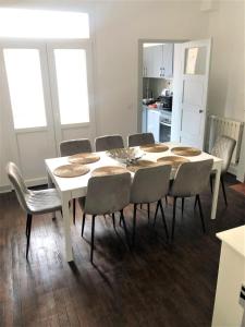 uma sala de jantar com uma mesa branca e cadeiras em Maison de ville avec cour Place Luton em Reims