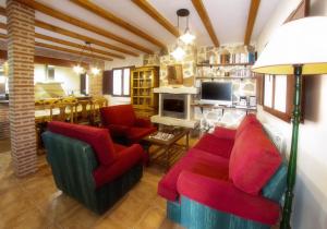 Casa Rural El Gorgocil في Puente del Congosto: غرفة معيشة مع كراسي حمراء ومدفأة