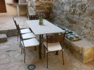 einen Tisch mit vier Stühlen und einer Steinmauer in der Unterkunft Casa Rural El Gorgocil in Puente del Congosto