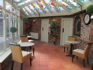 a conservatory with tables and chairs and a clock at Red Lion Coaching Inn in Epworth