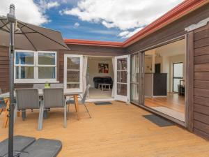 a patio with a table and chairs on a deck at Beach House on Hetherington - Whangamata Home in Whangamata