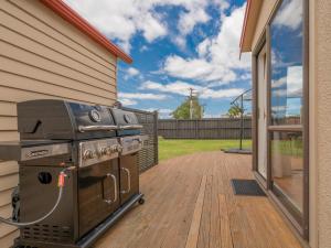 a grill on a deck next to a house at Beach House on Hetherington - Whangamata Home in Whangamata