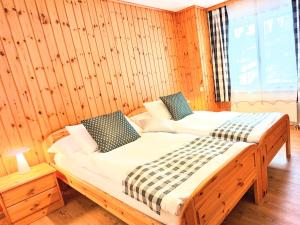 1 dormitorio con 2 camas en una pared de madera en Ferienwohnungen Wallis - Randa bei Zermatt en Randa