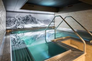 une piscine intérieure ornée d'une fresque murale représentant la montagne. dans l'établissement Precise Tale Seehof Davos, à Davos