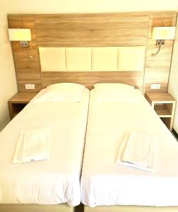 two beds in a room with white sheets at Hotel Les Pavillons Du Golfe in Favone +24 photos