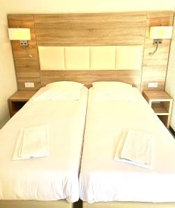 two beds in a room with white sheets at Hotel Les Pavillons Du Golfe in Favone