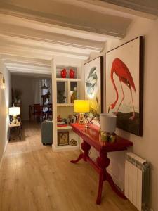 a living room with a table with a bird painting on the wall at Apto. centro histórico Huesca in Huesca