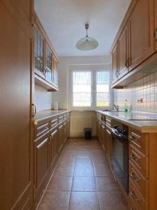 a large kitchen with wooden cabinets and a tile floor at Gästewohnung KL. WZL 40_4 