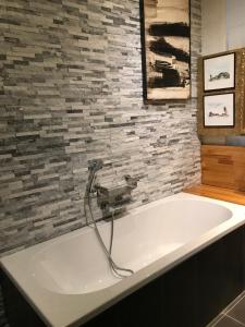 a bath tub in a bathroom with a stone wall at Caravaggio Boutique Suites in Antwerp