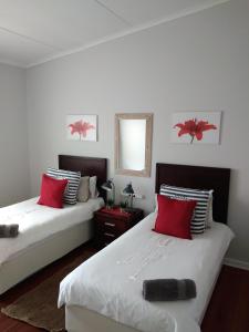 1 dormitorio con 2 camas con almohadas rojas y espejo en 20 on Beach Road en Swakopmund