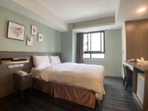 una camera d'albergo con un letto e una scrivania di Bonjour Hotel a Taichung