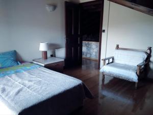 a bedroom with a bed and a chair and a window at Spacious rustic country house with sea view in Maronia