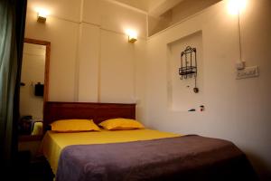 um quarto com uma cama com duas almofadas amarelas em Cornwall for Couple em Madikeri