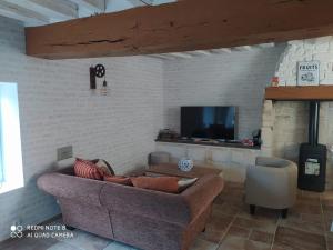 a living room with a couch and a tv at O’Pontpoint d’Autrefois in Pontpoint