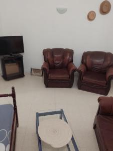 a living room with two leather chairs and a tv at Djerba house in Houmt Souk