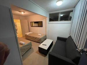 a small room with two beds and a couch at Mayfield Motel in Newcastle