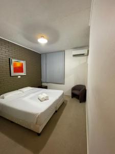 a bedroom with a large white bed and a chair at Mayfield Motel in Newcastle